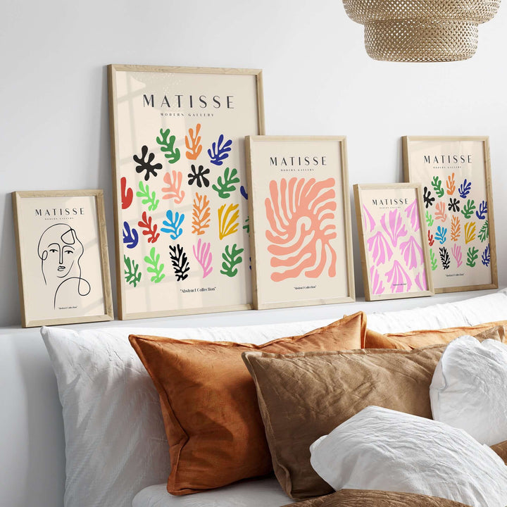 Matisse art prints featuring colorful abstract botanical shapes displayed on a shelf above a sofa with decorative pillows.