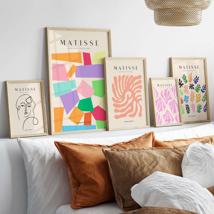 Colorful Matisse art prints showcasing geometric shapes and abstract designs on a chic shelf with cozy pillows.