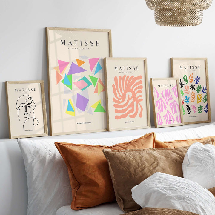 Matisse art prints featuring colorful geometric triangles and abstract designs displayed on a wall above cozy cushions.