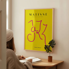 Matisse Art Prints - Jazz Pink Lettering Yellow Poster Art displayed on a wall with a person admiring it.