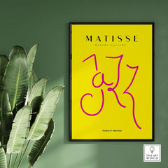 Matisse Art Prints - Jazz Pink Lettering Yellow Poster Art framed against a green wall with tropical leaves.