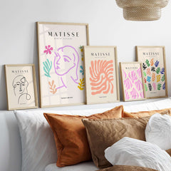 Matisse Art Prints -Line Art Face Abstract Botanical Collage Poster displayed on a wall above a cozy sofa with cushions.