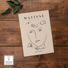 Matisse Art Prints -  Line Art Face Curly Hair Minimalist Poster displayed on a wooden surface with greenery.