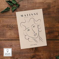 Matisse Art Prints -  Line Art Ladies Face with Wavy Hair Minimalist Poster on a wooden background with greenery.