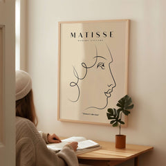 Matisse Art Prints -  Line Art of a Lady's Face Poster displayed on a wall with a woman admiring it.