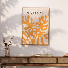 Matisse Art Prints - Orange Abstract Coral Pattern Poster displayed on a wall above a wooden table, showcasing a vibrant design.