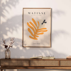 Matisse Art Prints - Orange Leaf Bird Silhouette Poster displayed on a wall, featuring bold orange shapes and a black bird silhouette.
