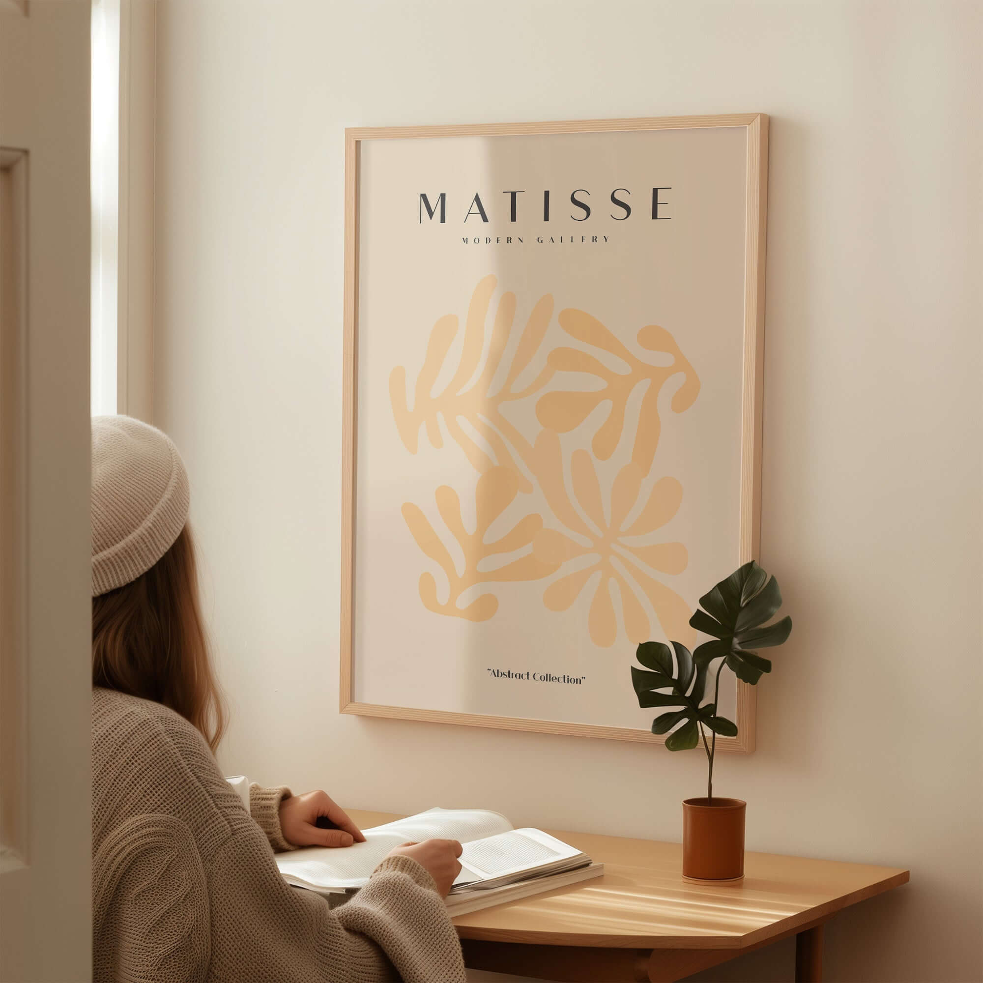 Matisse Art Prints - Pale Peach Abstract Shapes Wall Art displayed above a woman reading at a desk.