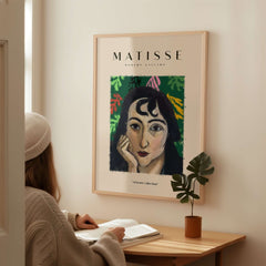 Matisse Art Prints - Pensive Woman Poster displayed on a wall, featuring a woman with dark curly hair against a green background.