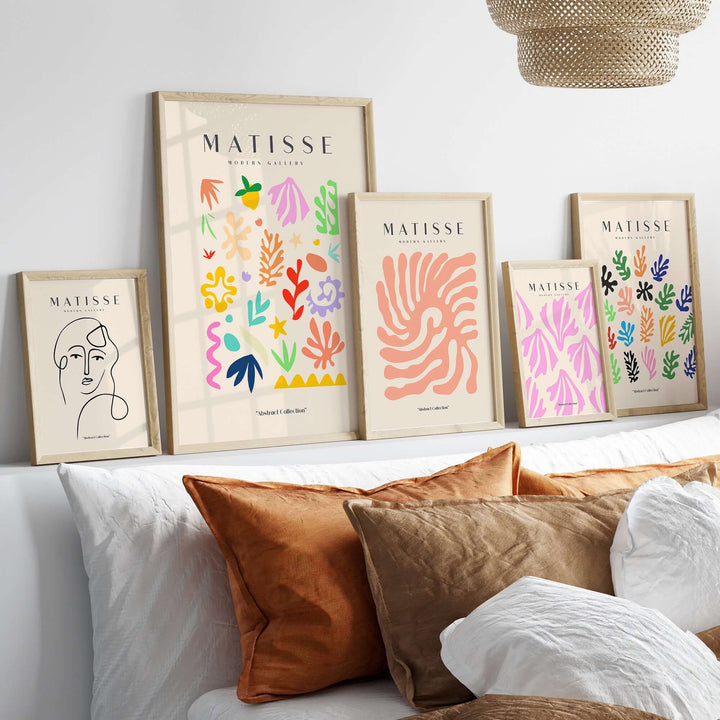 Colorful Matisse art prints featuring playful shapes displayed above a cozy bed with decorative pillows.