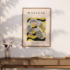 Matisse Art Prints - Resting Woman Patterned Blouse Yellow displayed on a wall above a stylish wooden console with decor.