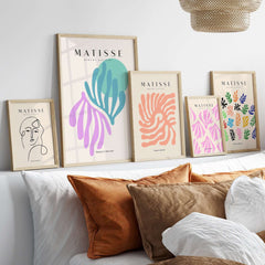 Matisse Art Prints -Teal Pink Abstract Leaves Sun Poster displayed on a wall above a couch with decorative pillows.