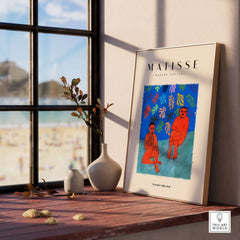 Matisse Art Prints - Two Figures Flute Poster displayed on a wooden table overlooking a beach, surrounded by decor.