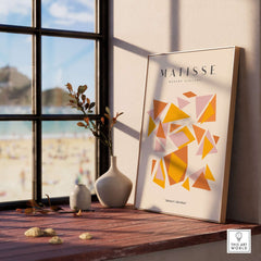 Matisse Art Prints - Warm Tone Geometric Triangles Poster displayed on a table by a window with beach view.