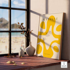 Matisse Art Prints -   Yellow Abstract Fluid Shape Poster displayed in a bright room with neutral decor and beach view.