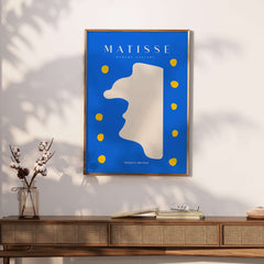 Matisse Art Prints -  Blue Abstract Profile with Yellow Dots Poster displayed in a modern setting with a wooden table.