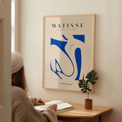 Matisse Art Prints - Blue Nude Abstract Cut Out Wall Art displayed in a cozy interior setting with a person reading.