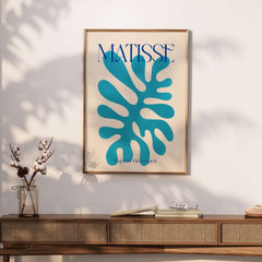 Matisse Cyan Blue Abstract Shape Papiers Découpés Poster displayed on a wall above a wooden console table.