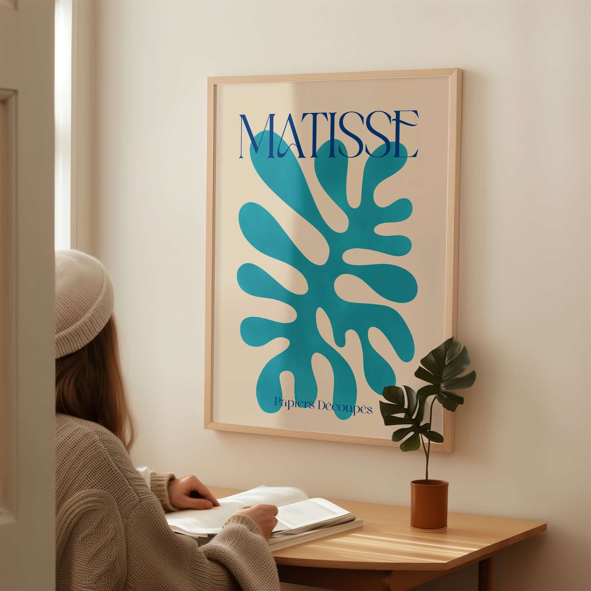 Matisse Cyan Blue Abstract Shape Papiers Découpés Poster displayed in a modern home setting with a person reading.