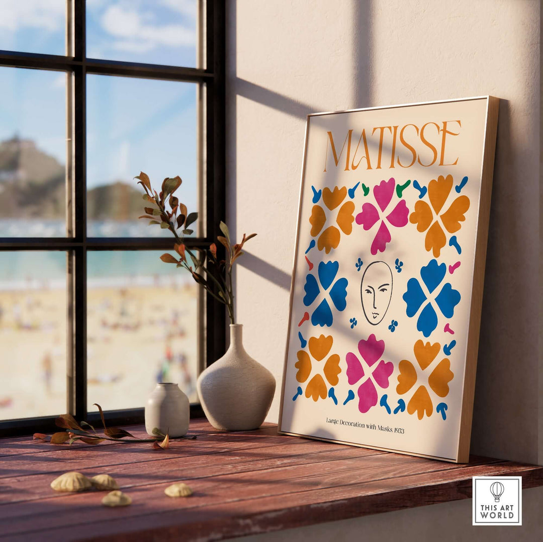 Matisse art print featuring masks and floral patterns in vibrant colors, displayed on a windowsill with beach view.