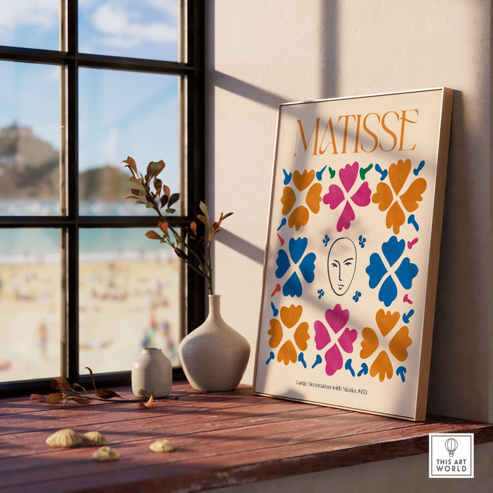 Matisse art print featuring masks and floral patterns in vibrant colors, displayed on a windowsill with beach view.