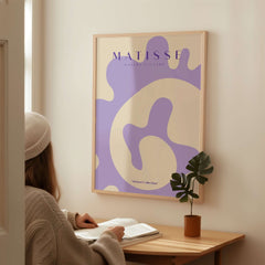 Matisse Art Prints -   Lavender Abstract Fluid Organic Shape Poster displayed in a cozy room with a plant.
