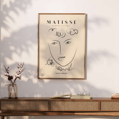 Matisse Art Prints -  Line Art Face Curly Hair Minimalist Poster displayed in a stylish interior with a wooden table.