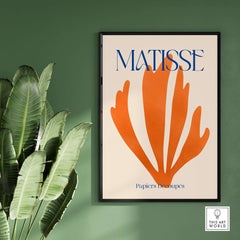 Matisse Papiers Découpés Orange Abstract Botanical Cut Out Art Print displayed on a green wall with palm leaves.