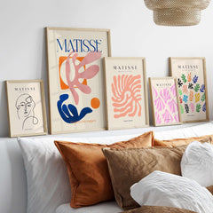 Matisse Papiers Découpés Pink Blue Abstract Art Print displayed on a wall above a cozy bed with decorative pillows.