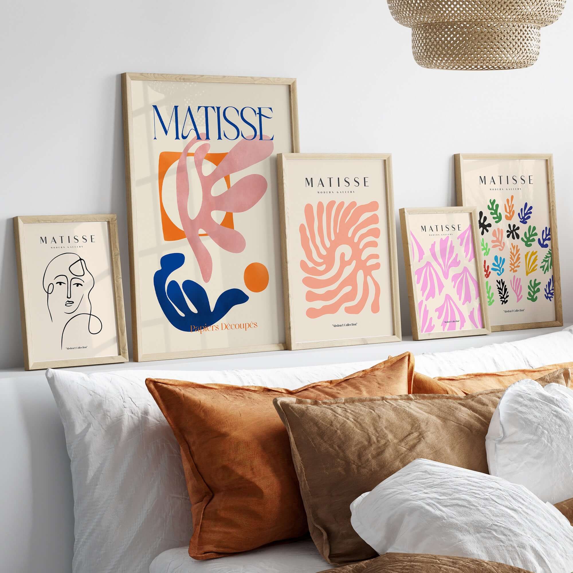 Matisse Papiers Découpés Pink Blue Abstract Art Print displayed on a wall above a cozy bed with decorative pillows.