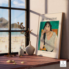 Matisse Poster - Laurette with a White Blouse 1917 Art Print displayed on a wooden shelf near a window.