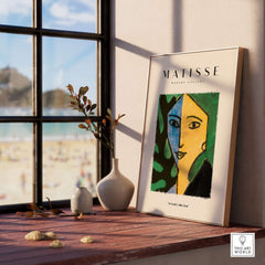 Matisse Art Prints - Split Face Blue Yellow Portrait Poster displayed on shelf with greenery and view of beach.