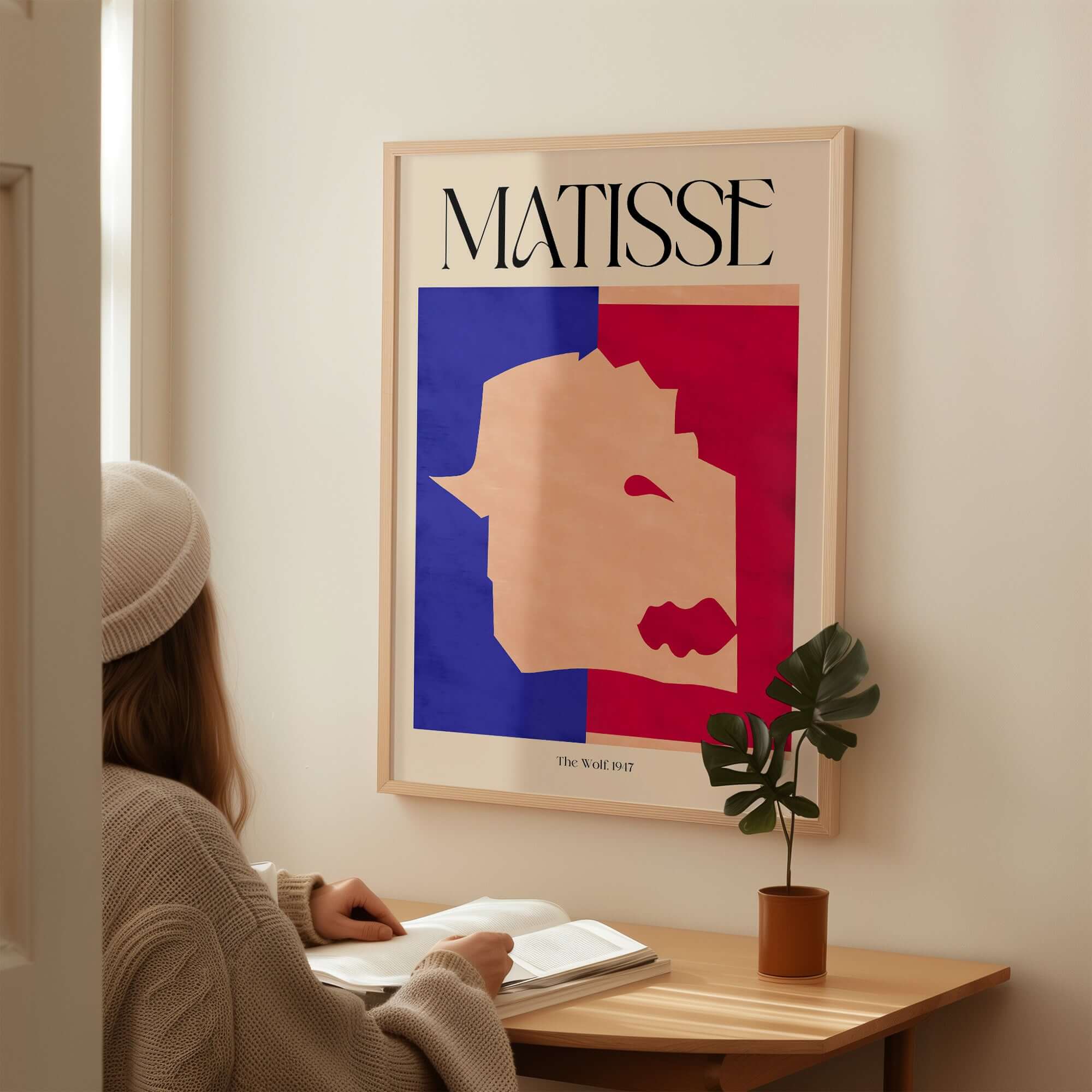 Matisse The Wolf 1947 Papiers Découpés Poster Print hanging above a person reading in a cozy setting.
