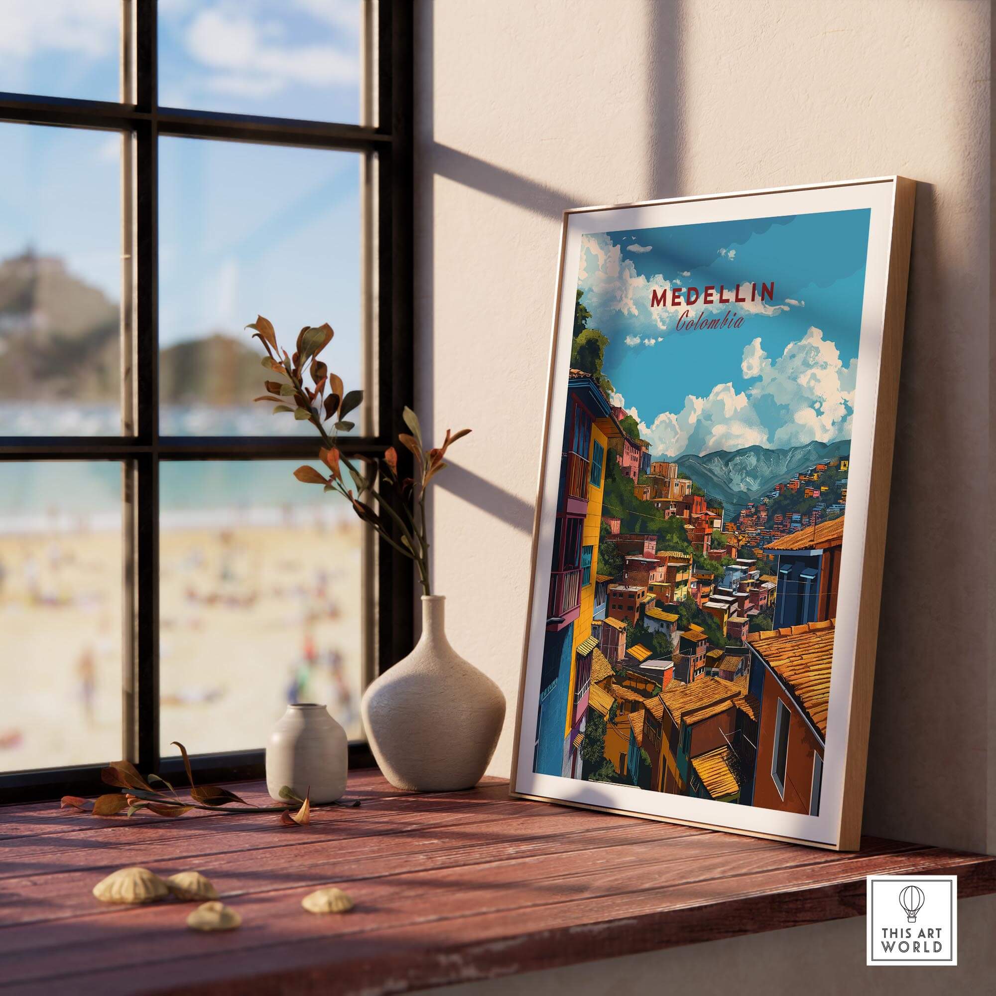 Medellin Travel Poster - Colombia displayed on a wooden table with a beach view, showcasing vibrant Colombian art.