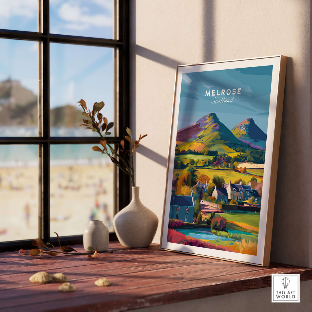 Framed Melrose Scotland travel print featuring Eildon Hills and village houses by a window.