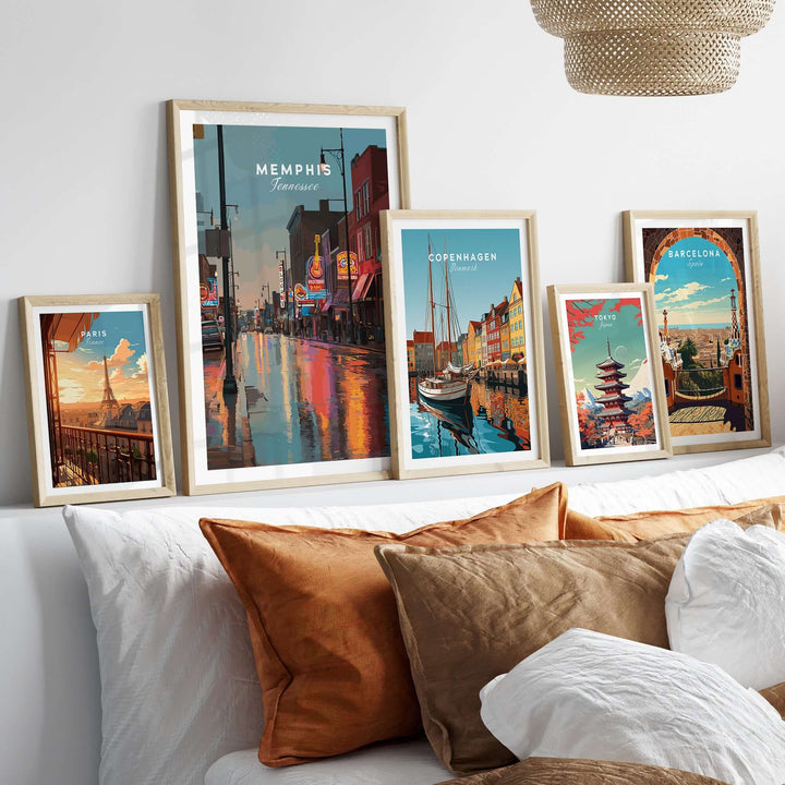 Framed art prints of Memphis, Copenhagen, and Barcelona displayed on a cozy sofa with decorative pillows.