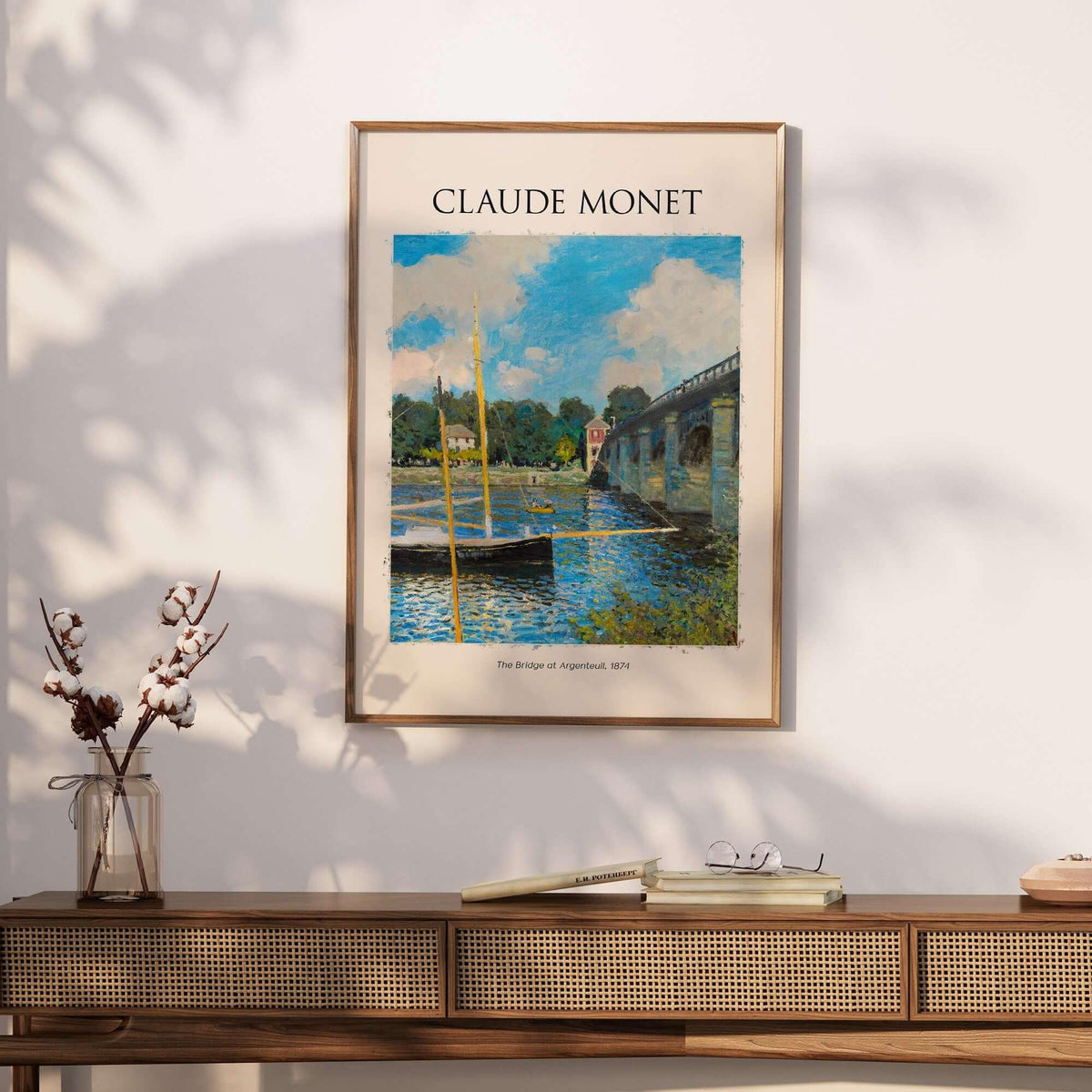 Monet The Bridge at Argenteuil Seine River Landscape Art Print Poster framed on a wall with a wooden table.