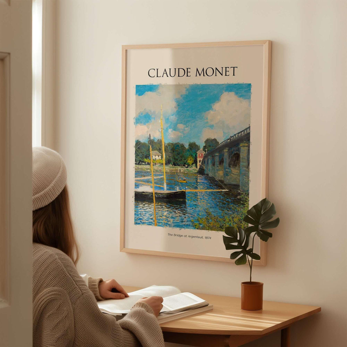 Monet The Bridge at Argenteuil Seine River Landscape Art Print Poster displayed on a wall with a person admiring it.