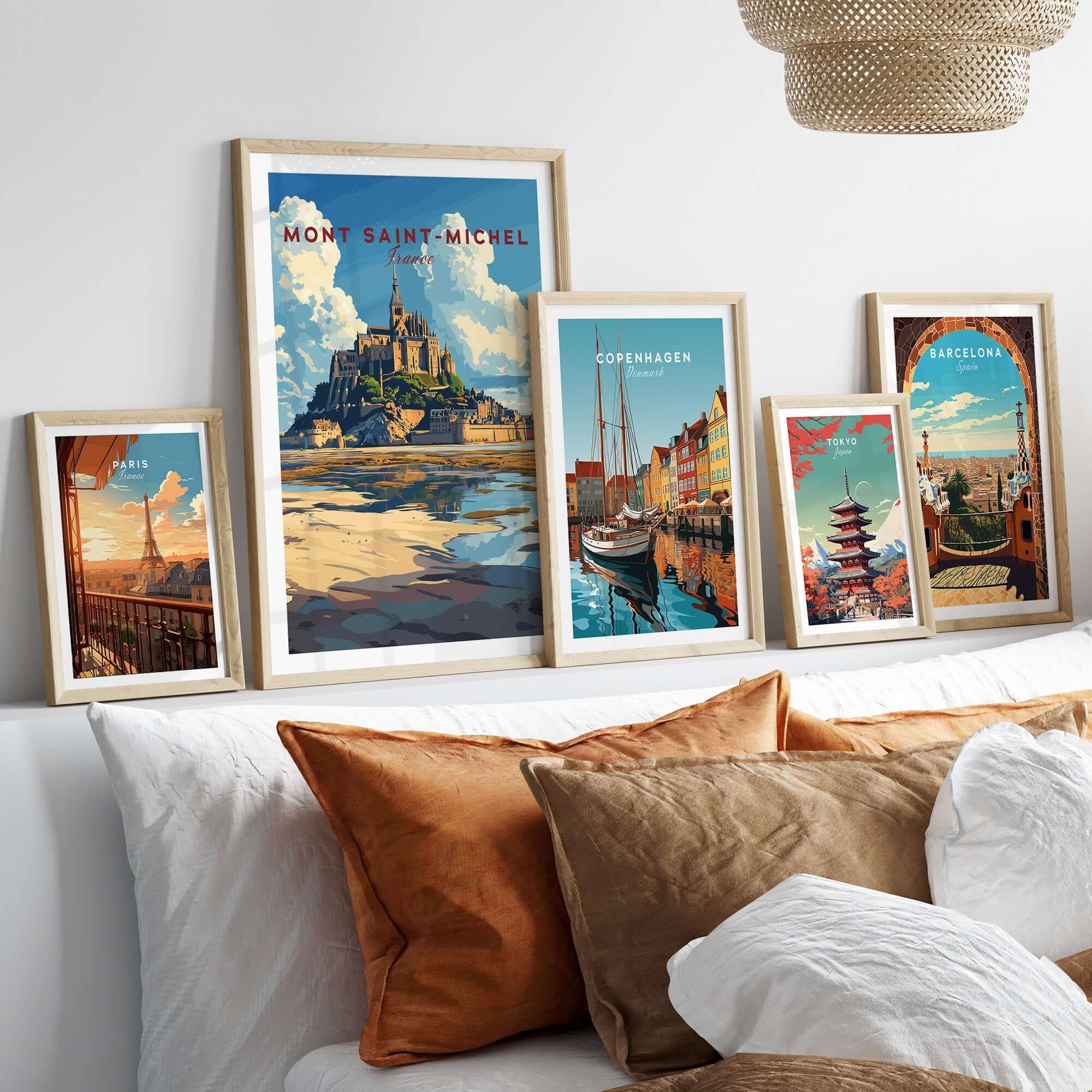 Mont Saint-Michel Wall Art Print and other travel posters displayed in elegant frames on a cozy bed.