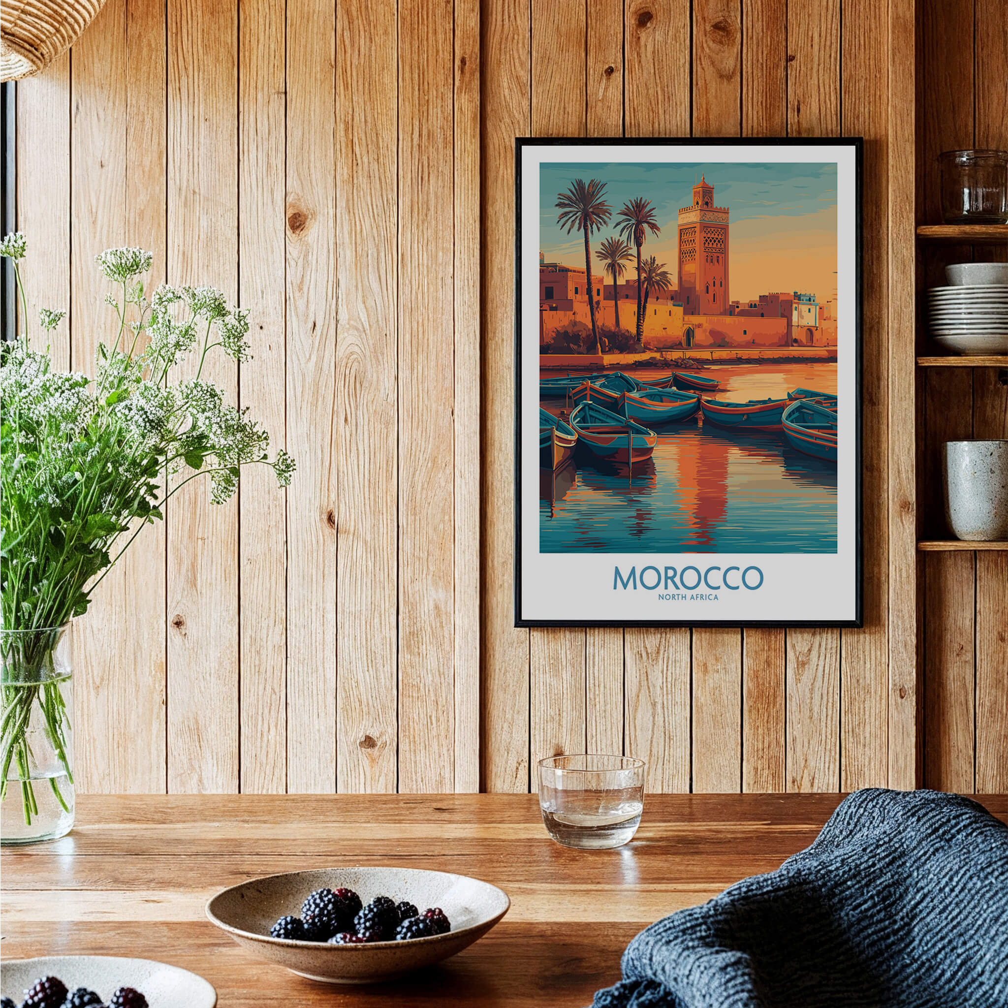Morocco Canvas Print | Traditional Blue Boat & Port Poster displayed on a wooden wall with plants and dishes.