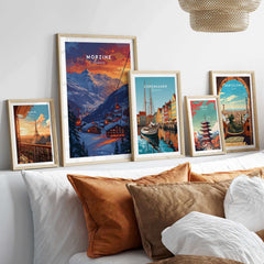 Framed ski posters including Morzine Print France displayed on a stylish shelf above a cozy bed with pillows.