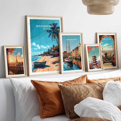 Mozambique Travel Poster displayed among other travel posters on a shelf with decorative pillows.