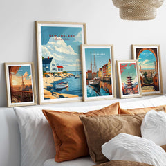 New England Travel Poster framed among other travel prints on a stylish wall above decorative pillows.