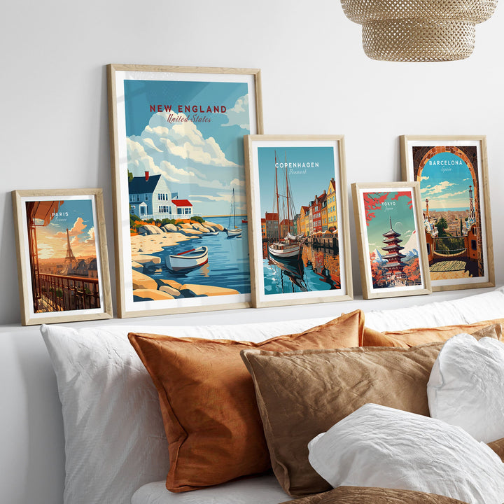 New England Travel Poster in frame displayed among other travel-themed wall art prints on a couch.