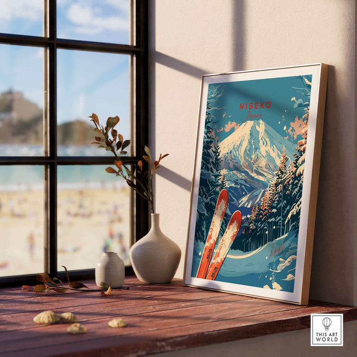 Framed Niseko Print Japan with snowy mountain and ski illustration on a sunlit windowsill.