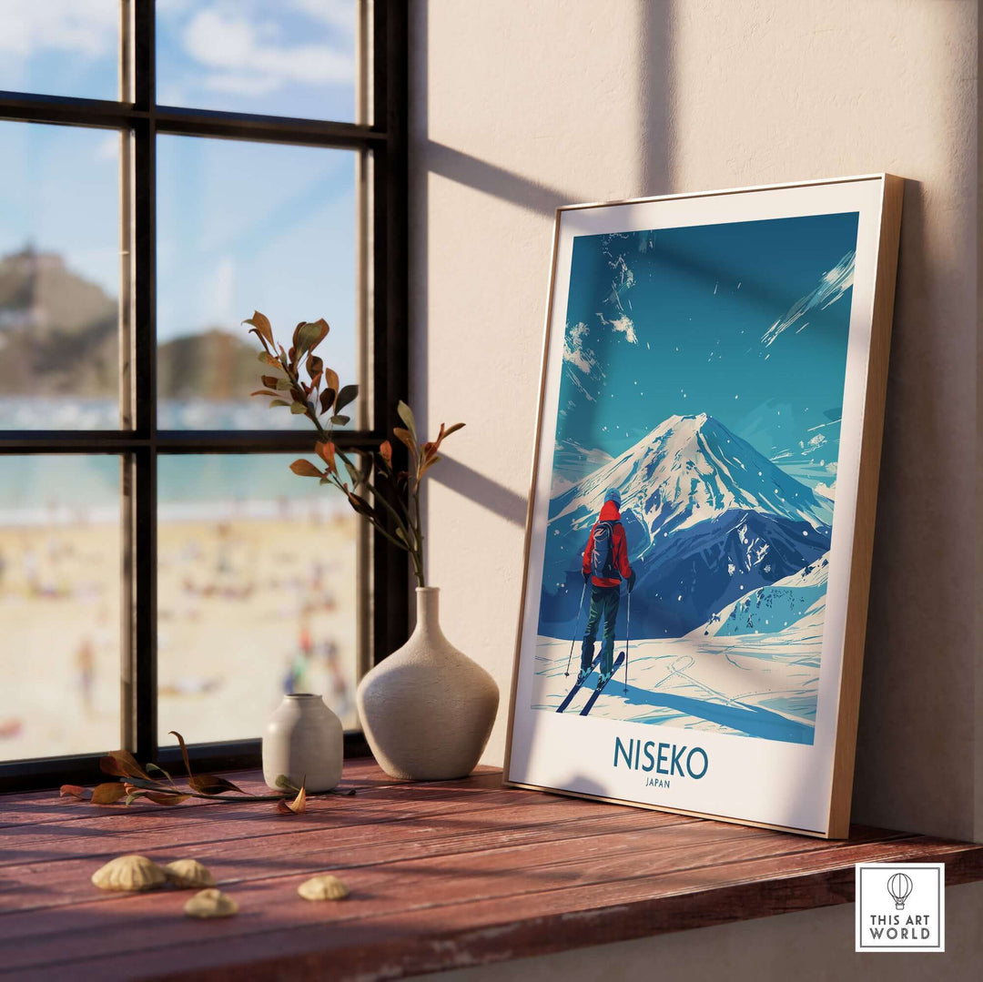 Niseko Ski Poster - Japan, featuring skier and snowy mountain, displayed on a windowsill with a beach view in the background.