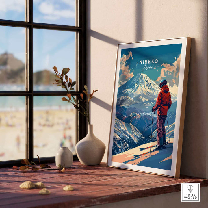 Scenic Niseko Japan wall art featuring a skier on a snowy mountain, displayed on a wooden table next to a window with beach view.