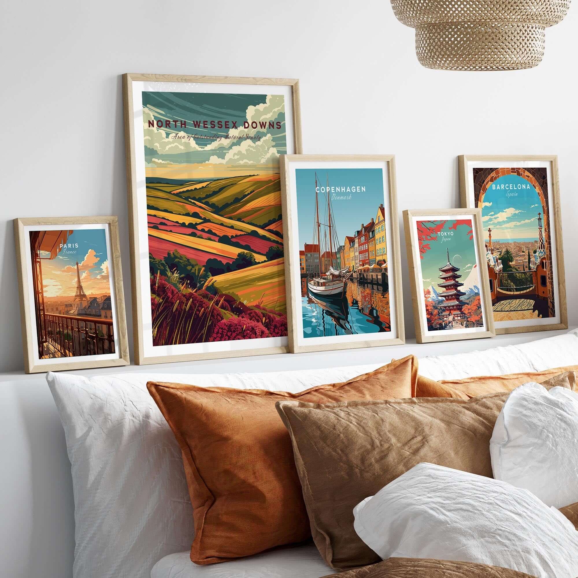 North Wessex Downs Wall Art Print surrounded by other travel-themed prints on a stylish bed with decorative pillows.