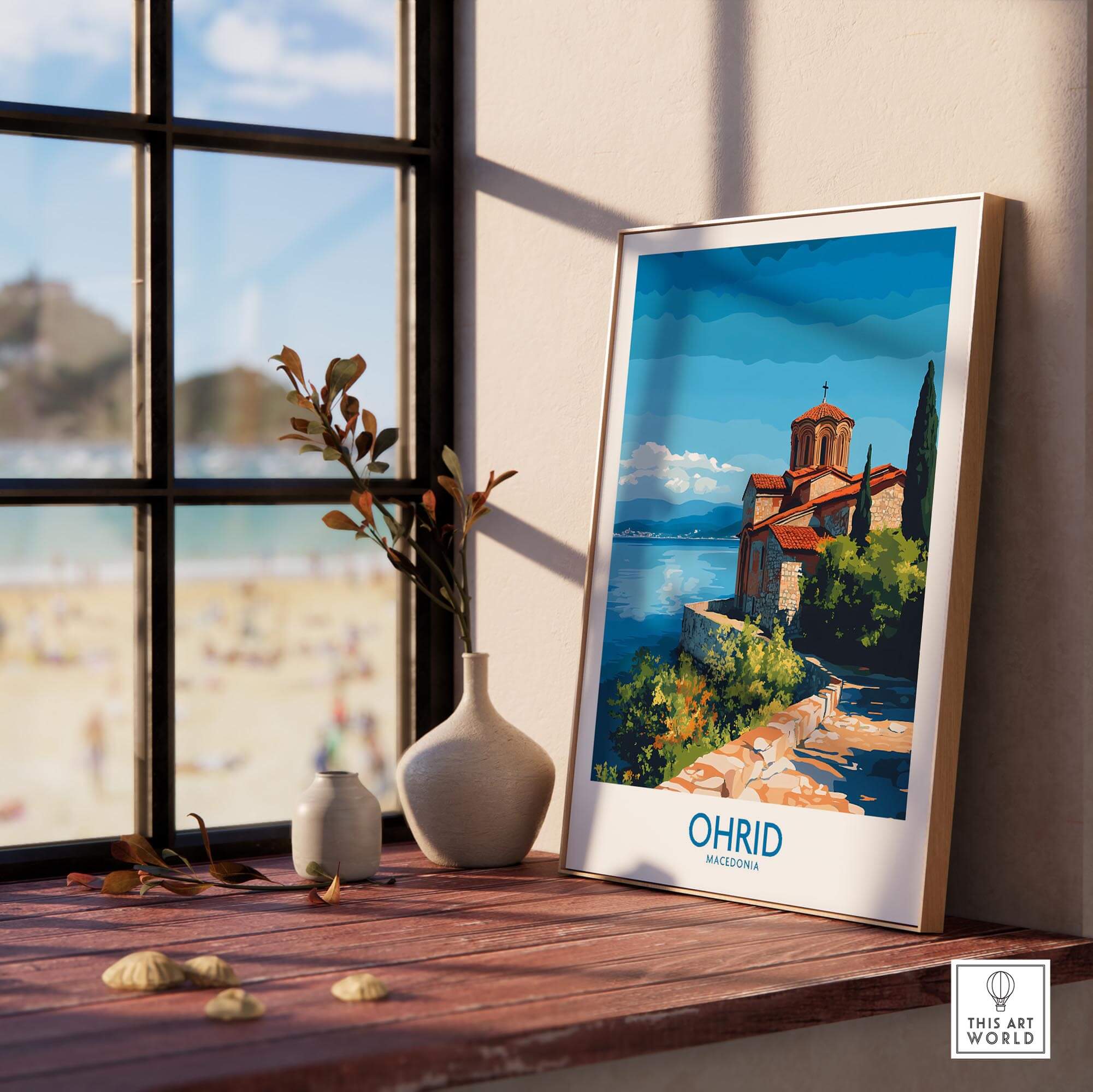 Ohrid Macedonia Wall Art Print displayed on a wooden table next to a vase and window with a beautiful lake view.