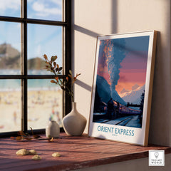Orient Express Vintage Train Art Print framed poster displayed on a wooden shelf beside a window with a scenic view.